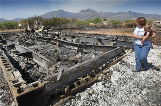 Gayle Gehr along with grandson Nathan Jacob look at their burned home that was destroyed from the Monument Fire near Sierra Vista, Ariz. on Wednesday.